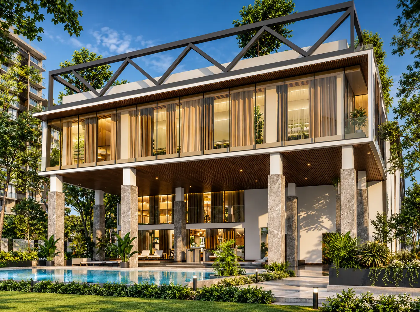 The clubhouse at dusk, its glass upper floor glowing above a turquoise pool and stone-clad columns.